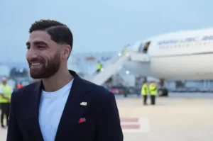 Iran Datang Dengan Pesan; Mari Membuka Mata pada Tragedi di Balik Pesta Dunia 1 Pemain Timnas Iran tiba di bandara mengenakan jas gelap dengan sematan pin 168 di kerah jasnya untuk Piala Dunia 2026.